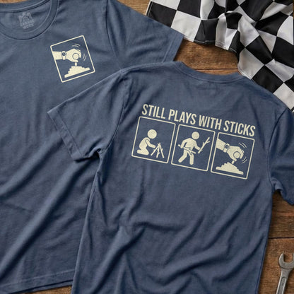 Blue t-shirt with "Still Plays With Sticks" and three stick figure icons.