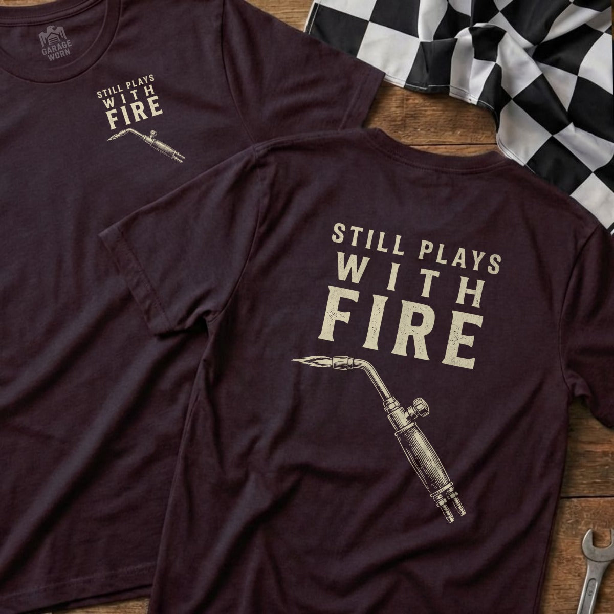 Burgundy t-shirt with "Still Plays With Fire" and a torch graphic.