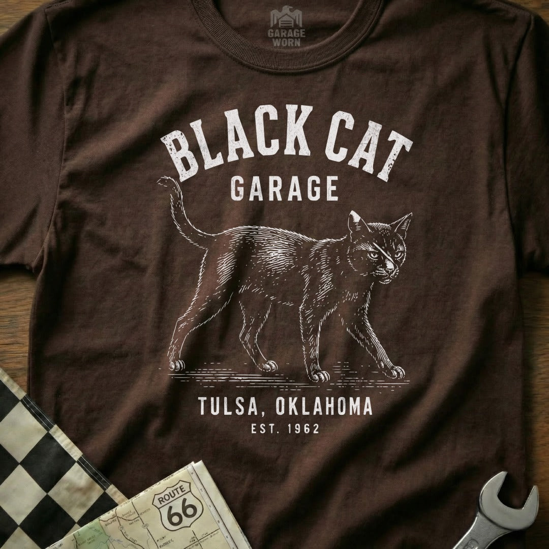 Brown t-shirt with "Black Cat Garage Tulsa, Oklahoma Est. 1962" text and a walking cat graphic.