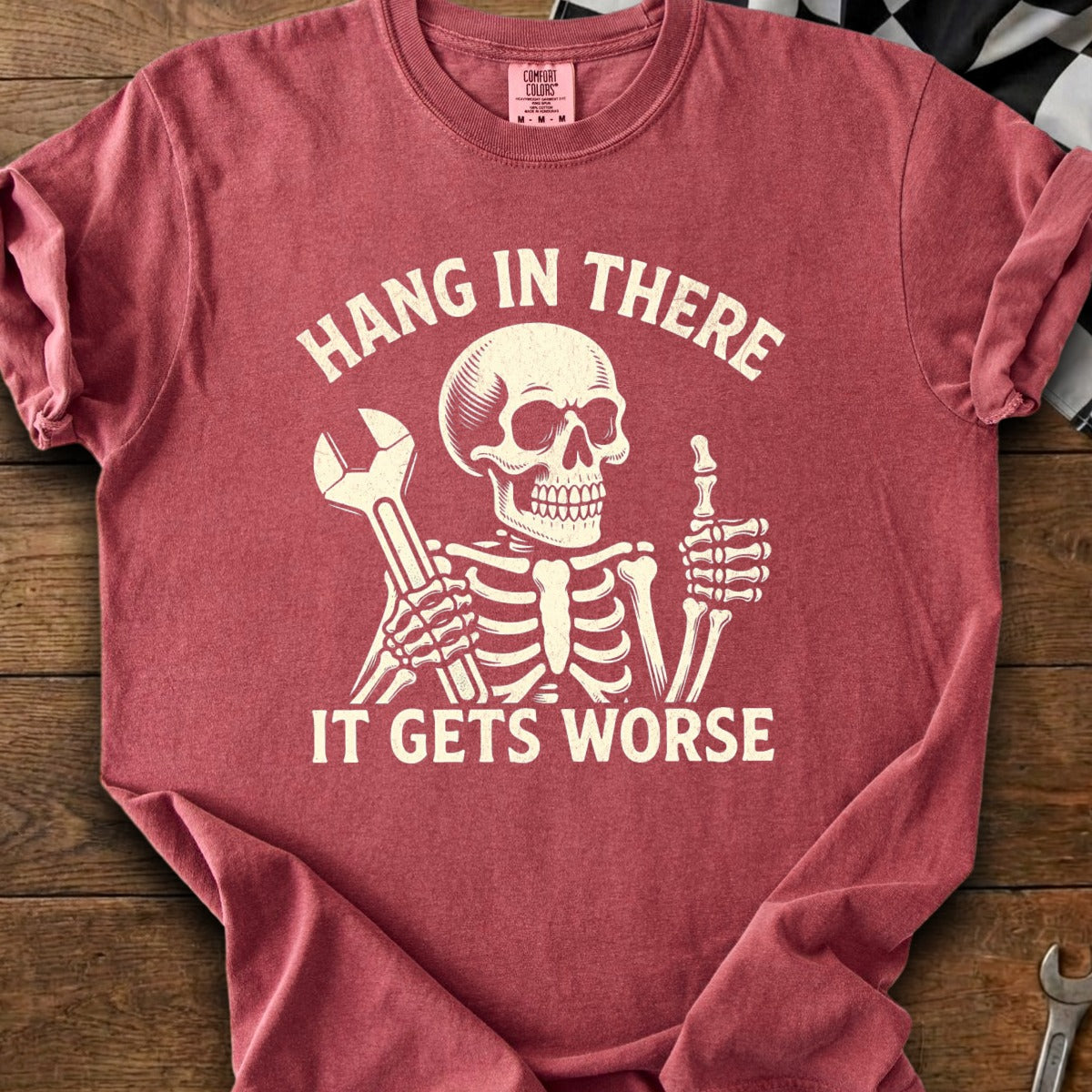 Skeleton holding wrench, giving thumbs up, with text "HANG IN THERE IT GETS WORSE"