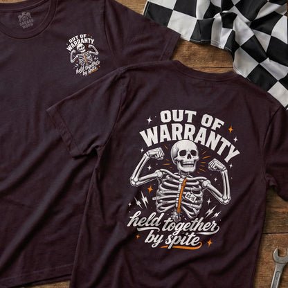 Dark t-shirt with "Out of Warranty, Held Together by Spite" text and a skeleton graphic.