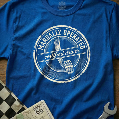 Blue t-shirt with "Manually Operated Certified Driver" graphic and clutch pedal.