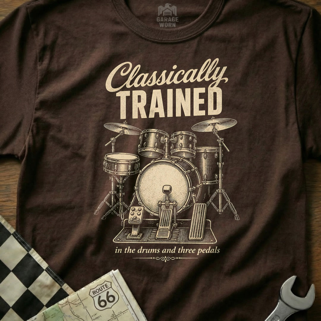 Brown t-shirt with "Classically TRAINED in the drums and three pedals" and drum set graphic.