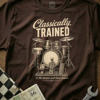 Brown t-shirt with "Classically TRAINED in the drums and three pedals" and drum set graphic.