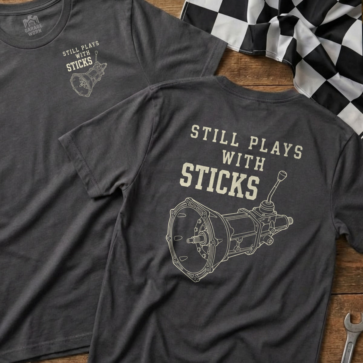 T-shirt with "Still Plays with Sticks" and manual transmission graphic.