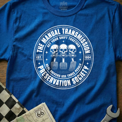Blue t-shirt with "The Manual Transmission Preservation Society" design featuring three skulls and pedals.
