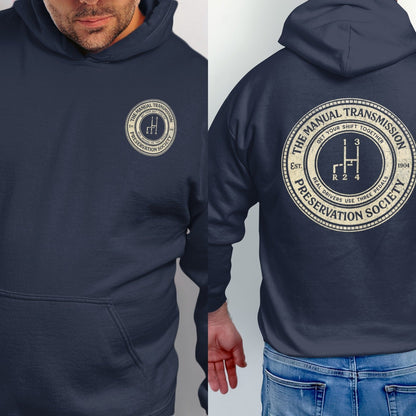 Navy hoodie featuring a circular logo with a manual transmission shift pattern, "The Manual Transmission Preservation Society," and "Real drivers use three pedals."