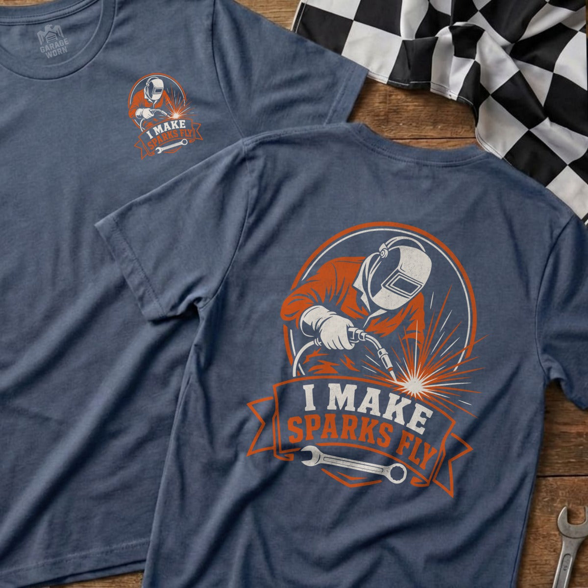 Blue t-shirt with a graphic of a welder and the text "I MAKE SPARKS FLY".