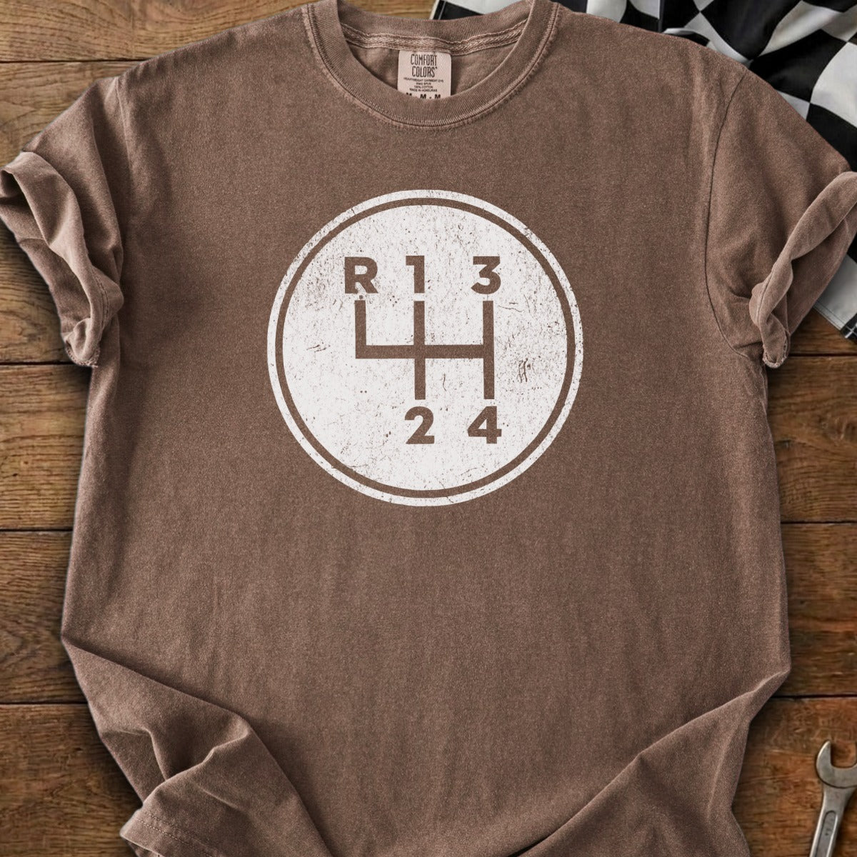 Brown t-shirt with a circular graphic of a manual car transmission shift pattern.