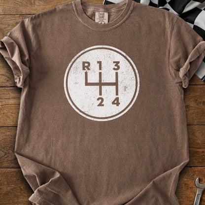 Brown t-shirt with a circular graphic of a manual car transmission shift pattern.