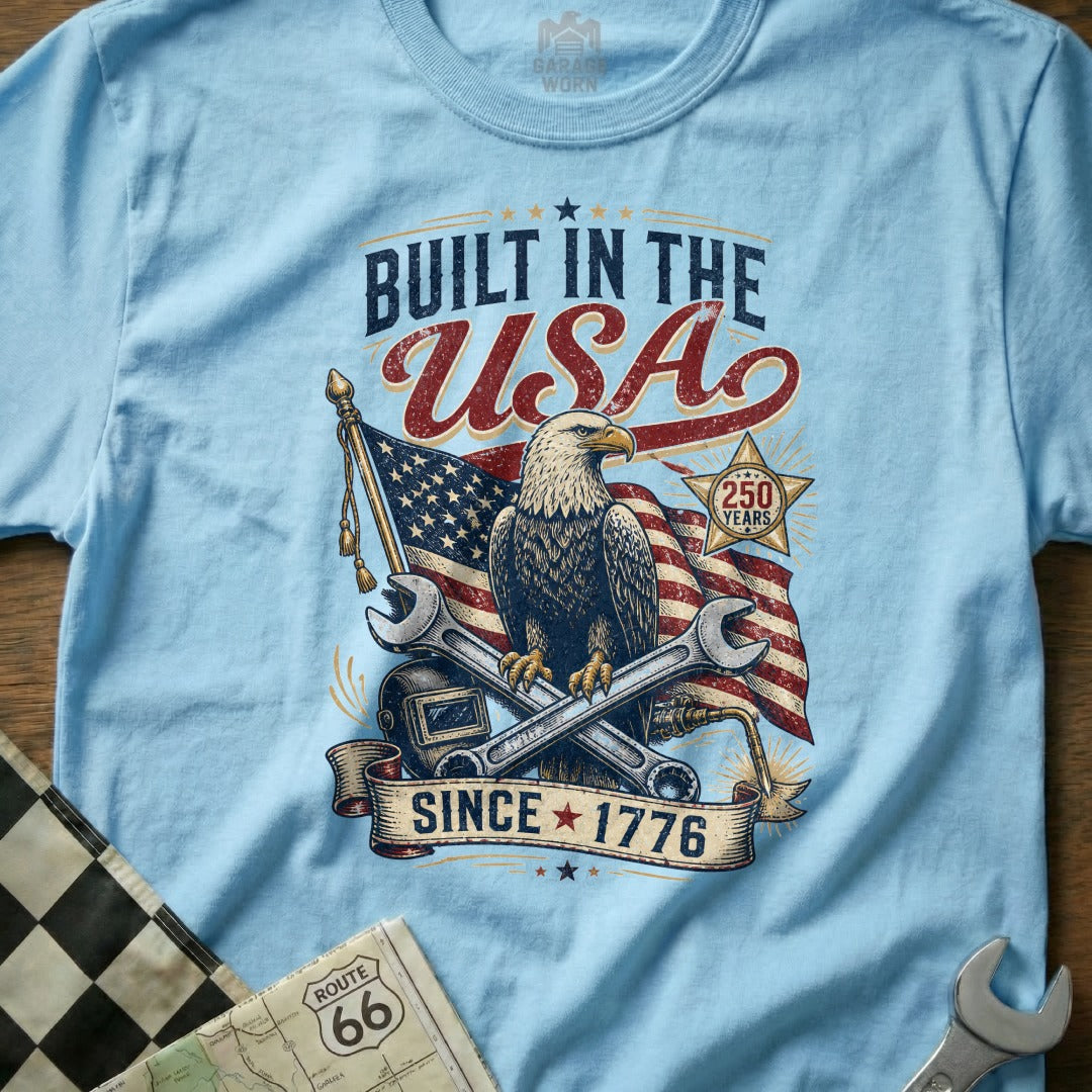 Light blue t-shirt with patriotic eagle, flag, tools: "Built in the USA Since 1776".