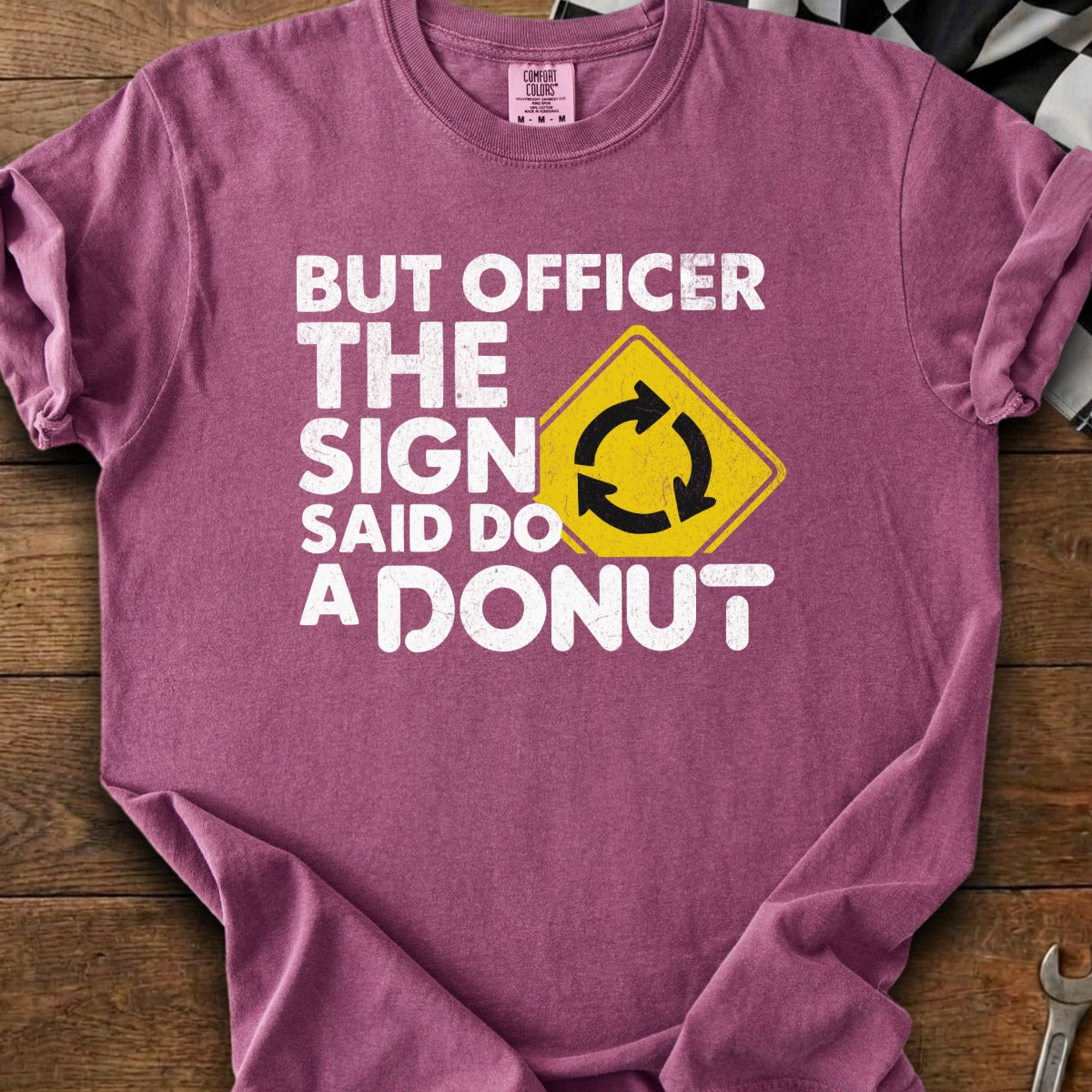 T-shirt with white text "BUT OFFICER THE SIGN SAID DO A DONUT" and a roundabout sign.