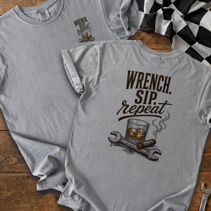 Gray t-shirt with "Wrench. Sip. Repeat." slogan and illustration of whiskey, cigar, and tools.