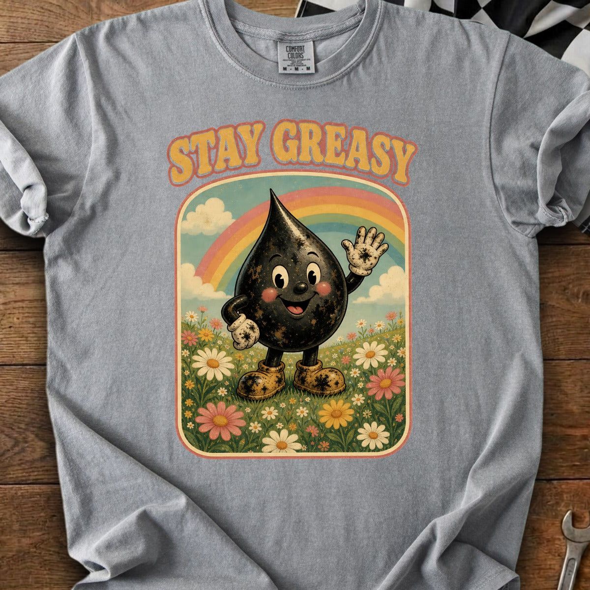 Grey t-shirt with "STAY GREASY" text and cartoon oil drop character in a field of flowers.