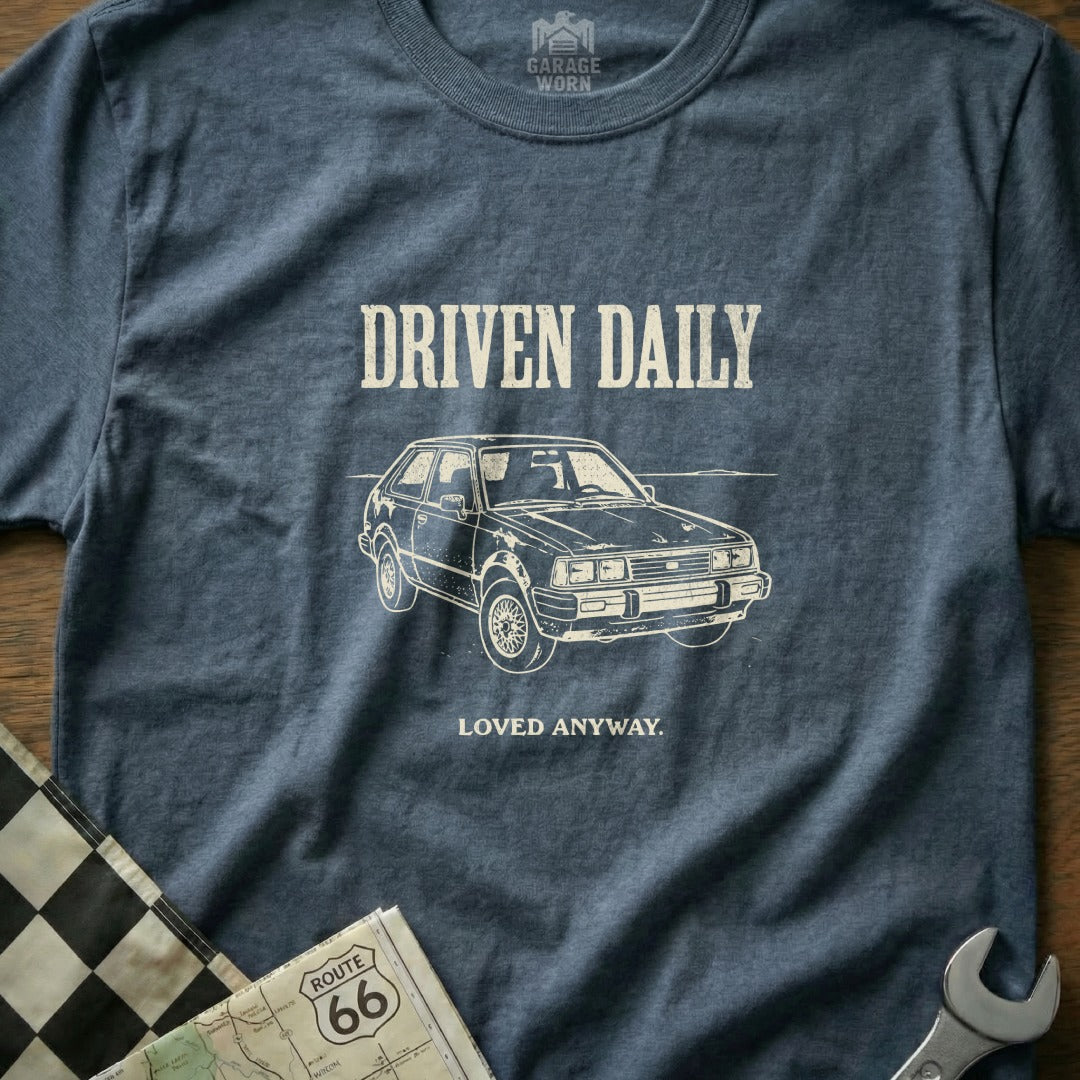 T-shirt with "DRIVEN DAILY LOVED ANYWAY" text and vintage car graphic.