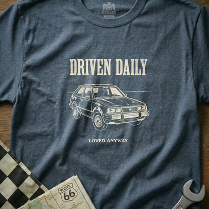 T-shirt with "DRIVEN DAILY LOVED ANYWAY" text and vintage car graphic.