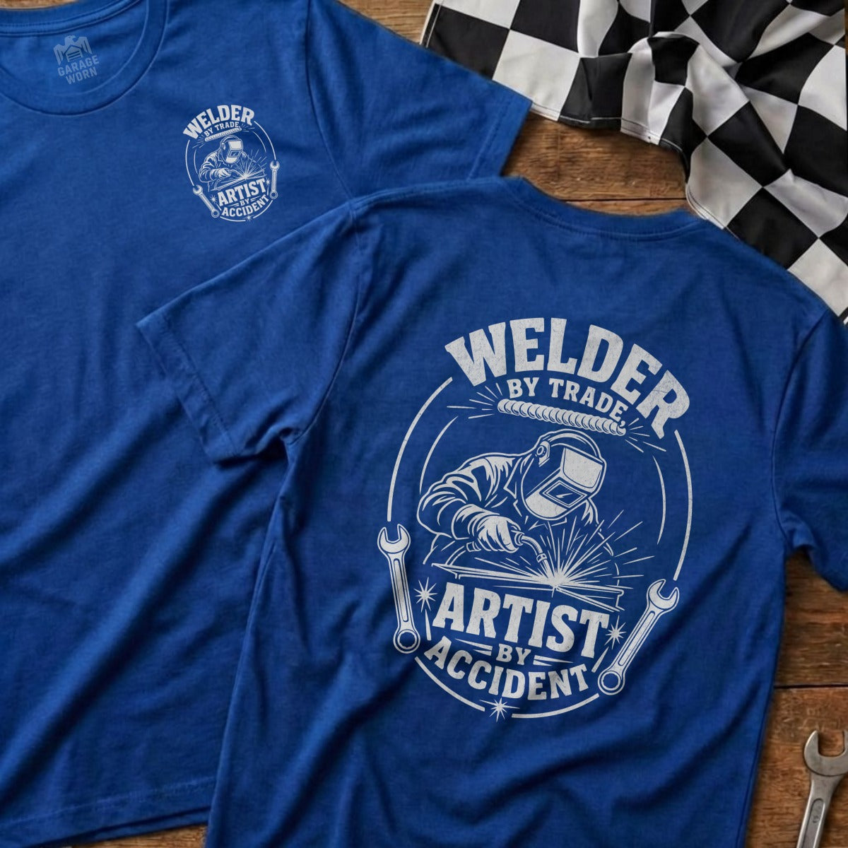 Blue t-shirt with "Welder by Trade, Artist by Accident" graphic.