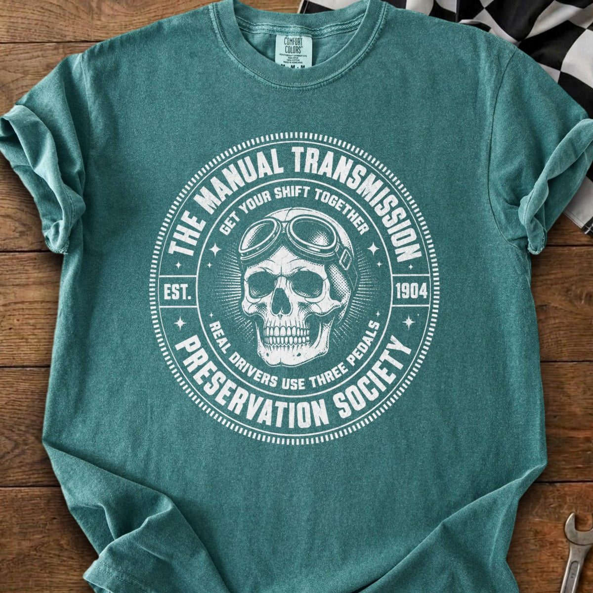 Teal t-shirt with a skull wearing goggles and text about manual transmissions.
