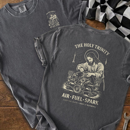 Dark grey t-shirt with "The Holy Trinity" graphic of Jesus working on an engine.