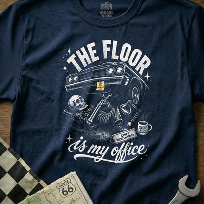 Navy t-shirt with skeleton mechanic fixing car, text "The floor is my office."