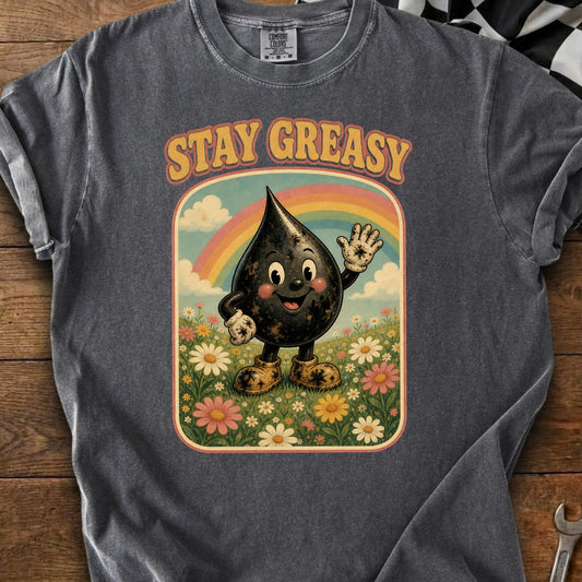 T-shirt graphic with cartoon oil drop character, rainbow, and flowers, text says "STAY GREASY".