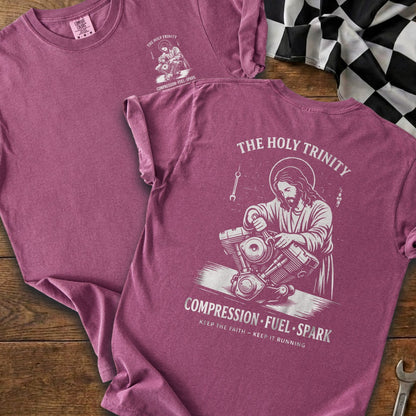 Jesus working on a motorcycle engine with "The Holy Trinity" text above.