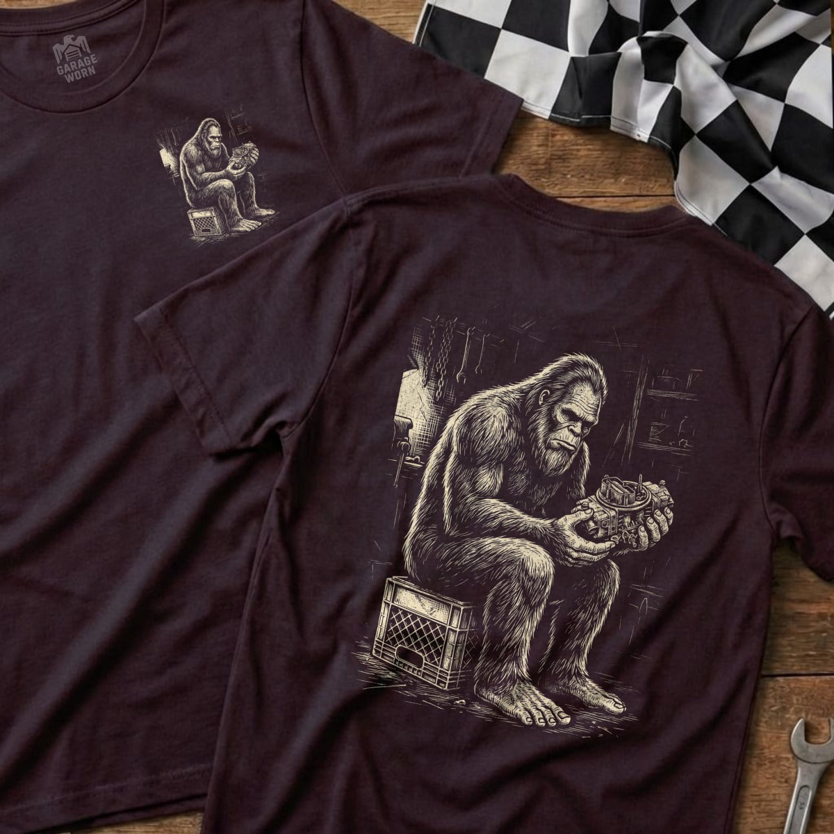 T-shirt with Bigfoot sitting on a crate, holding a carburetor.