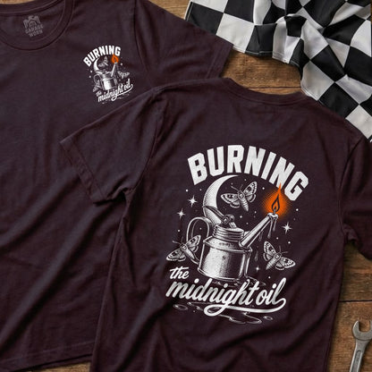T-shirt graphic with a watering can, moths, moon, and "Burning the midnight oil" text.