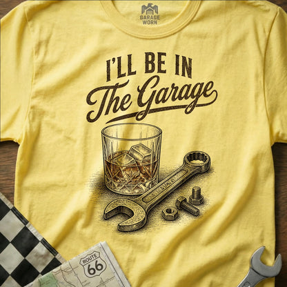 Yellow t-shirt with "I'll be in the Garage" print, a glass of ice, and a wrench.