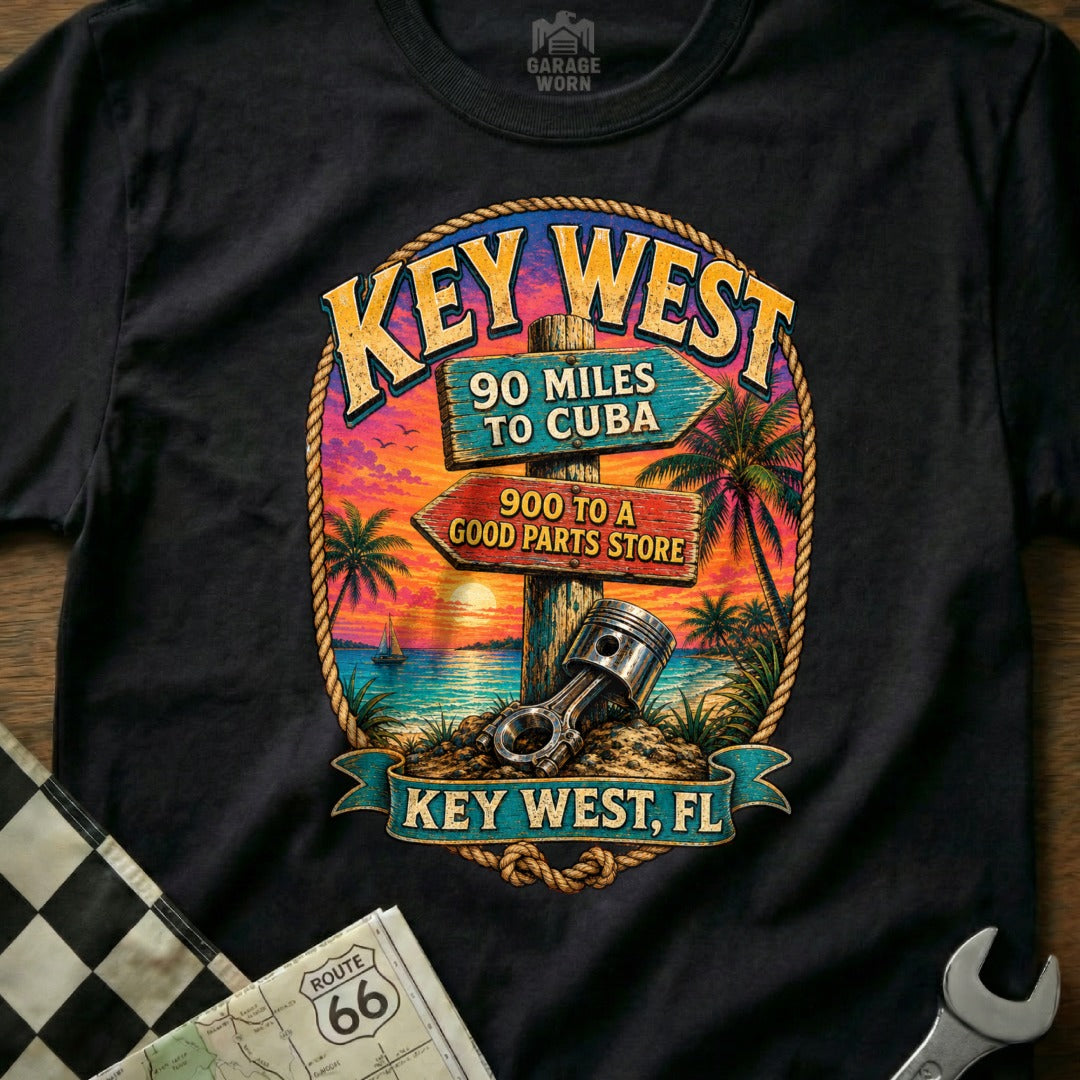Key West, FL graphic with directional signs and car piston on black t-shirt.