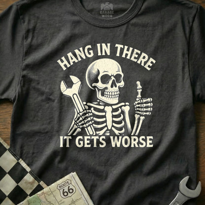 Skeleton with wrench gives thumbs up on dark t-shirt with text "Hang in there it gets worse".