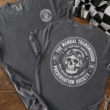 Dark gray t-shirt with a skull and goggles logo that reads "The Manual Transmission Preservation Society".