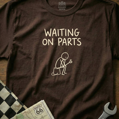 Brown t-shirt with "WAITING ON PARTS" in white text and stick figure holding a bolt.