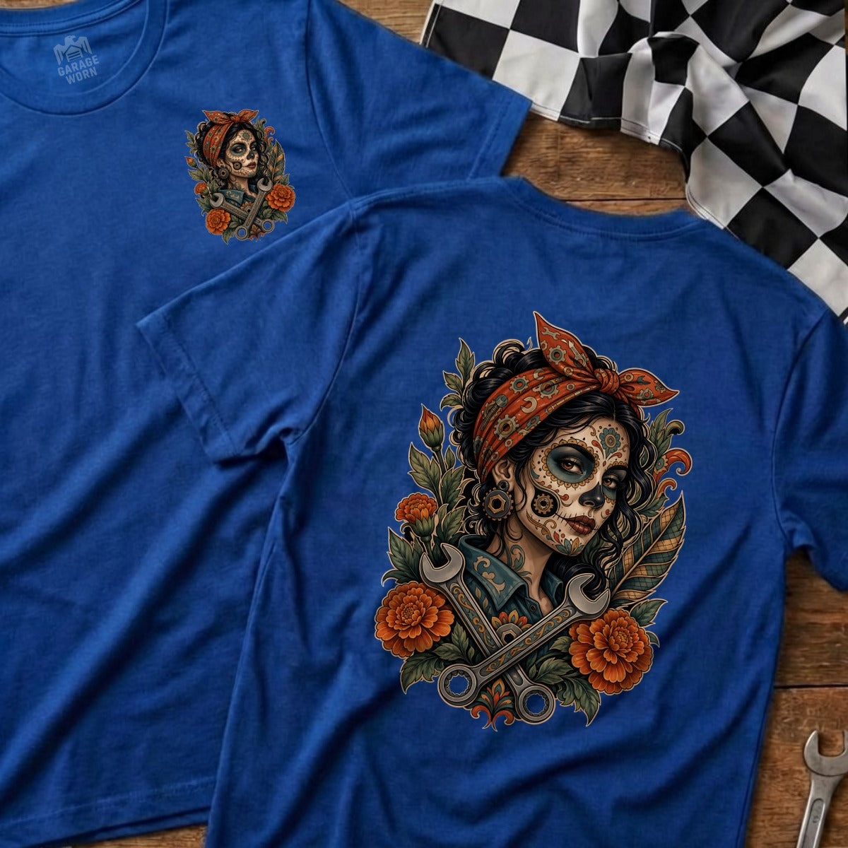 Blue t-shirt with graphic of a woman in Day of the Dead makeup, wrenches, and flowers.