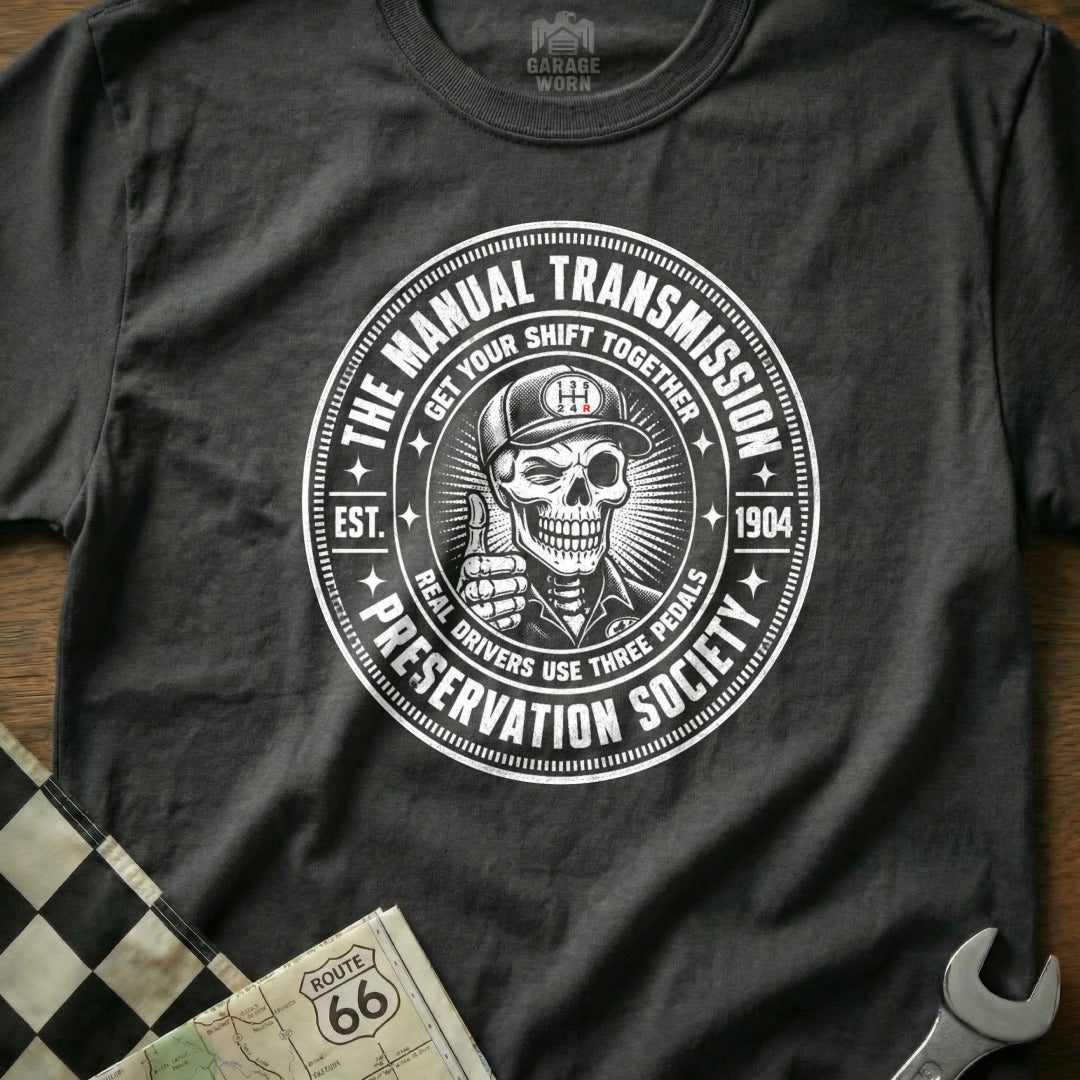 T-shirt graphic: Skeleton wearing a cap, giving a thumbs-up, with "Manual Transmission Preservation Society" text.