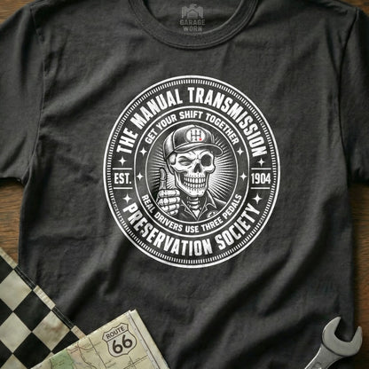 T-shirt graphic: Skeleton wearing a cap, giving a thumbs-up, with "Manual Transmission Preservation Society" text.