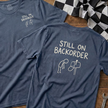 Blue t-shirt with "Still on Backorder" text and a stick figure at a mailbox.