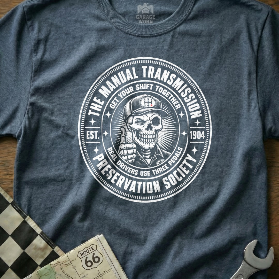 Distressed circular graphic with skeleton giving thumbs up, "Manual Transmission Preservation Society."