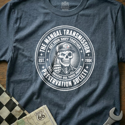 Distressed circular graphic with skeleton giving thumbs up, "Manual Transmission Preservation Society."