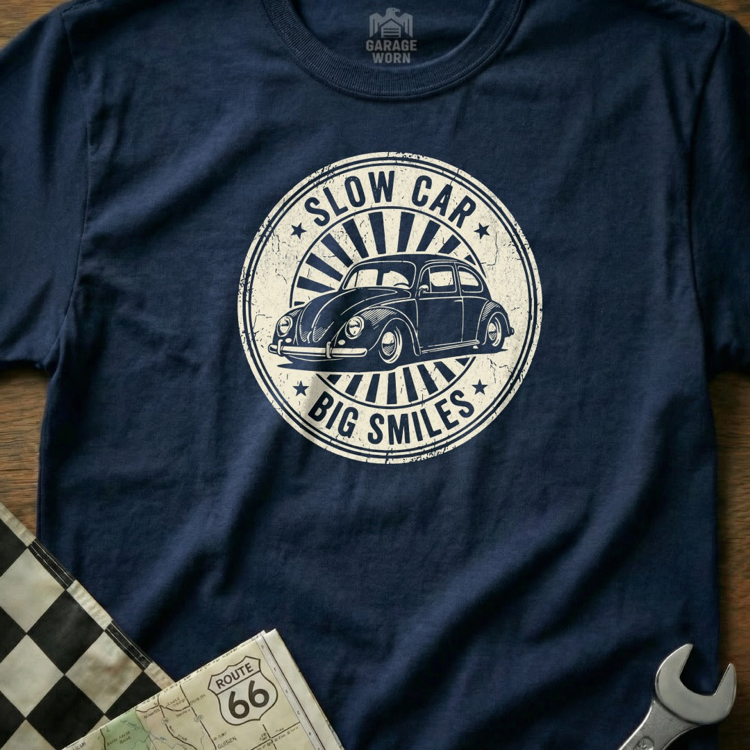 Navy t-shirt with a circular graphic of a Volkswagen Beetle and text "Slow Car, Big Smiles."