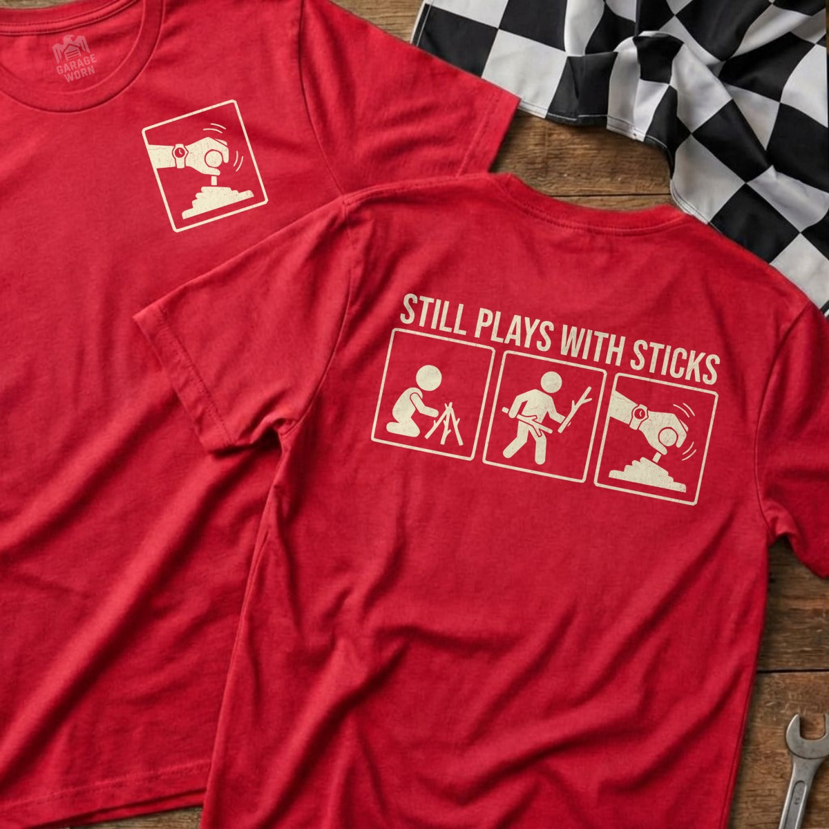 Red t-shirt with "Still Plays With Sticks" and stick figure graphic.