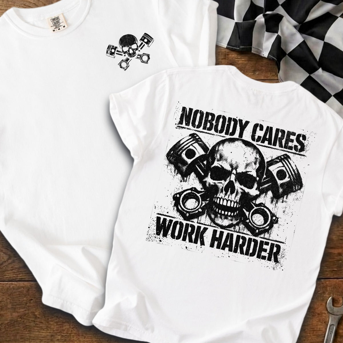 White t-shirt with graphic of skull and pistons, text "Nobody Cares Work Harder".