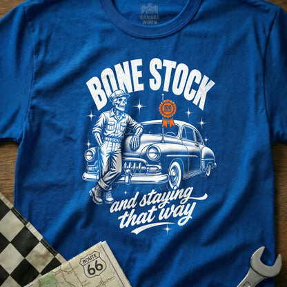 T-shirt with skeleton leaning on vintage car, "Bone Stock" text, and "100 Percent" medal.
