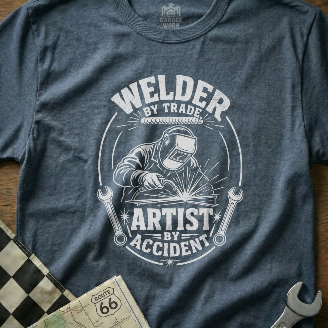 T-shirt with white graphic: "Welder by Trade, Artist by Accident" with welder illustration.