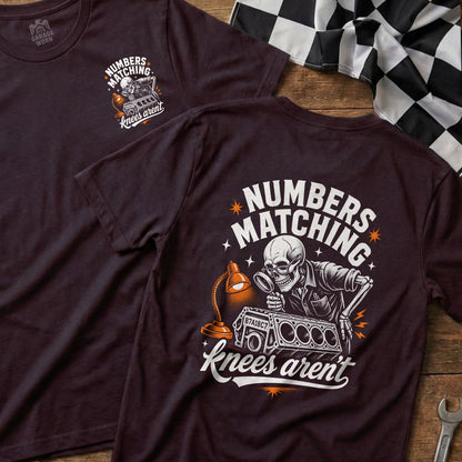 Dark t-shirt with "NUMBERS MATCHING knees aren't" graphic of a skeleton inspecting an engine.