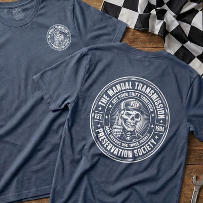 Blue t-shirt with white graphic of a skull giving a thumbs up and "The Manual Transmission Preservation Society" text.