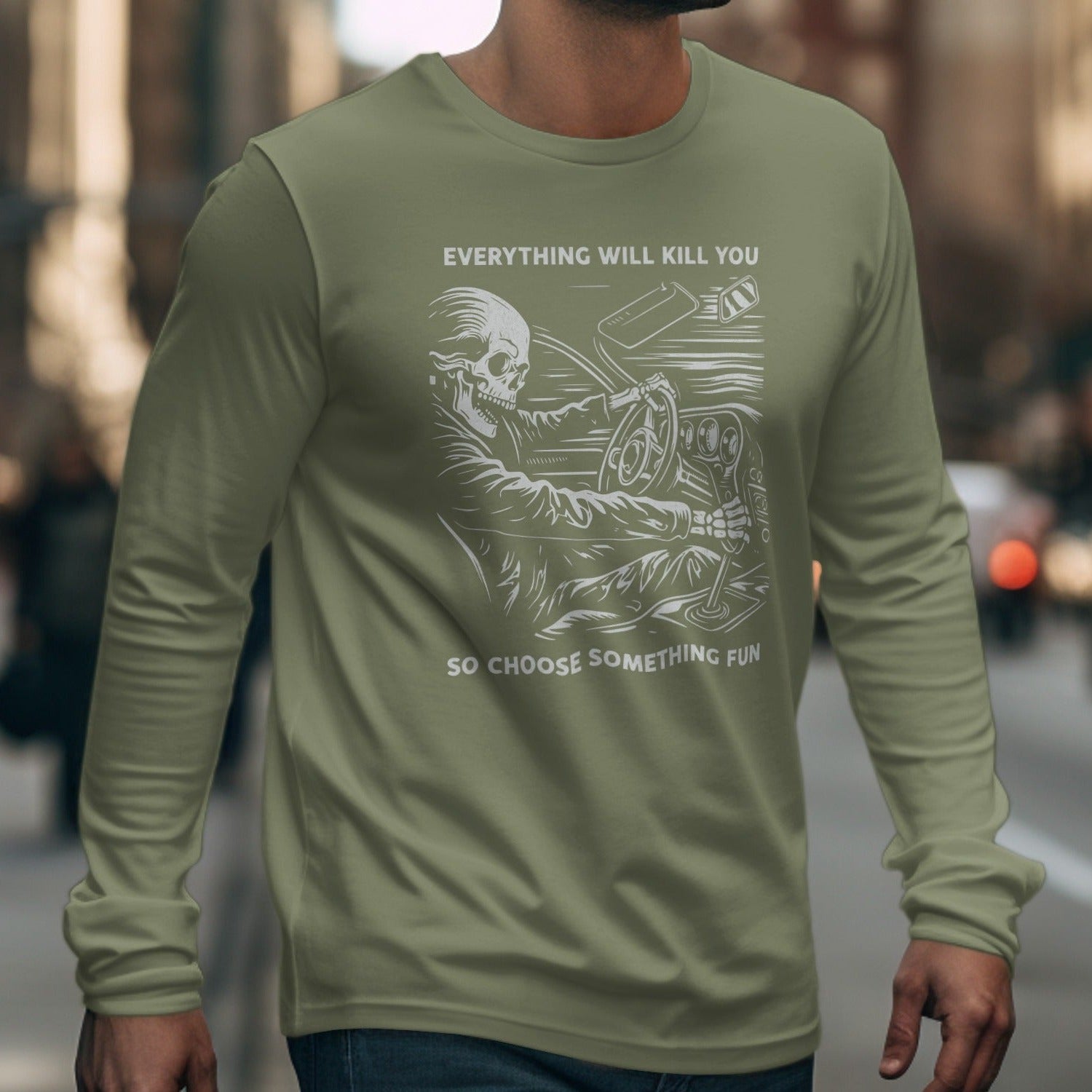 Olive green long-sleeve shirt with skeleton driving, text "Everything will kill you so choose something fun".