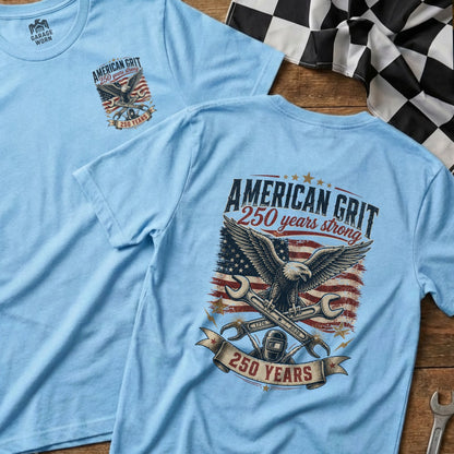 Light blue t-shirt with eagle, American flag, wrenches, and "American Grit 250 years strong" text.