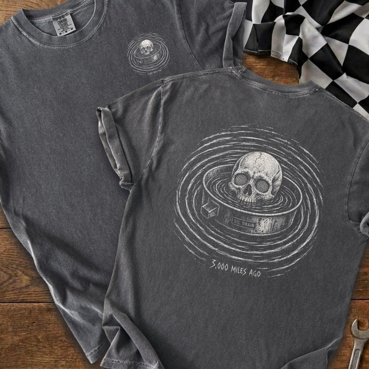 Dark t-shirt with skull in oil drain graphic and text "3,000 Miles Ago".