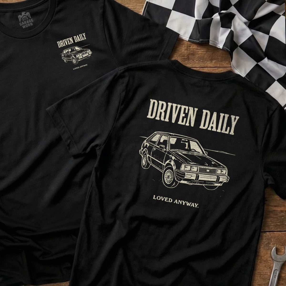 Black t-shirt with "Driven Daily" and car graphic on back, and logo on sleeve.